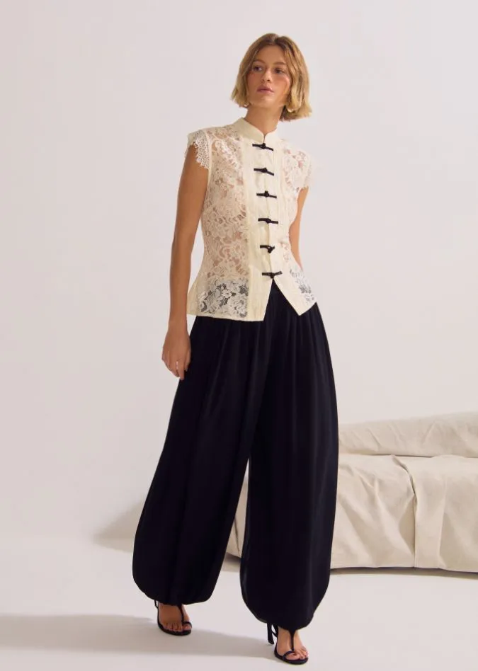 Modelo com blusa de renda e calça preta, da coleção da Le Blog